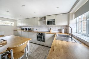 a kitchen with white cabinets and a wooden table at Host & Stay - Great Habton Cottage in Malton
