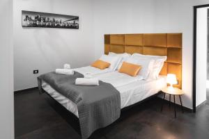 een slaapkamer met een groot bed met witte lakens en oranje kussens bij HIŠA KAPIŠ with HOT TUBE in Koper