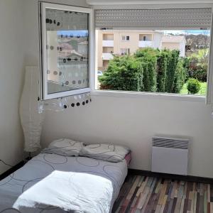 Habitación pequeña con cama y ventana en Spacieux appartement résidence calme, en Fonsorbes