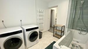 uma máquina de lavar roupa na casa de banho ao lado de uma banheira em Chez Sandrine & Tanguy em Saint-Valery-sur-Somme