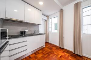 a kitchen with white cabinets and a wooden floor at Ribeira do Esmeraldo by Homie in Funchal