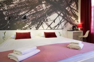 a bedroom with a white bed with towels on it at Art Hotel Like in Zagreb