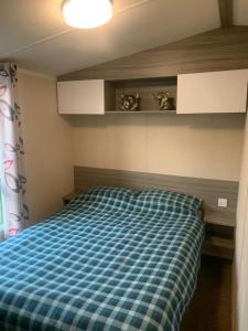 a bedroom with a bed with a blue checkered blanket at Littlesea haven Rachel’s retreat in Wyke Regis