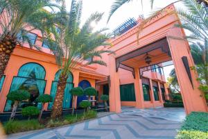 an orange building with palm trees in front of it at Amman Unique Hotel - SHA Plus in Udon Thani