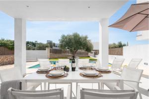 Biały stół i krzesła na patio z parasolem w obiekcie STUNNING VILLA MARIANELLA GRIS, POOL, BBQ, AC, FREE WIFI w mieście Cala d´Or