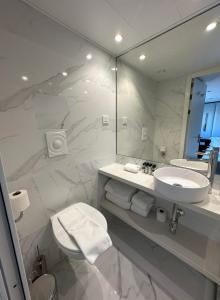 W białej łazience znajduje się umywalka i lustro. w obiekcie Costa do Sal Hotel Boat Lounge w mieście Aveiro