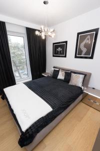 - une chambre avec un grand lit et une couverture noire dans l'établissement Apartament Business&Living No 73 z prywatnym jacuzzi zewnętrznym -od maja do września- Nad Zalewem w Cedzynie i miejscem parkingowym, à Cedzyna