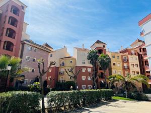 una fila de edificios con árboles y palmeras en Apartment Los Gavilanes en Isla Canela