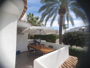a table with an umbrella on a balcony with a palm tree at Camino del Vasco in Denia