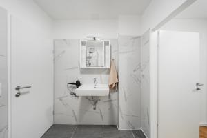 a white bathroom with a sink and a mirror at Modern Central City Rooms in Vienna