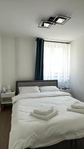 a bedroom with a white bed with two towels on it at Bogdan's Ultracentral Residence 1 in Timişoara