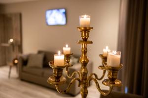 two gold candlesticks with candles in a living room at Hôtel de la Tour in Melen
