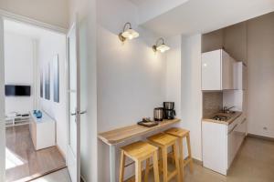 una pequeña cocina con armarios blancos y taburetes de madera en Elizabeth Garden Apartment, en Budapest