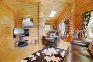 una sala de estar con sofá y TV en una cabaña de madera en Faweather Grange en Bingley