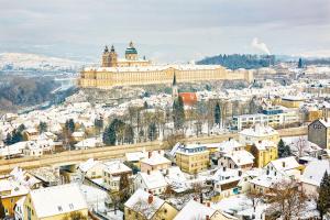 a city with snow covered buildings and a castle at Melker Apartment in Melk
