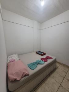 a room with a bed with two clothes on it at Espaçosa kitnet em itapua 10 min da praia. in Vila Velha