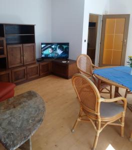 ein Wohnzimmer mit einem TV, einem Tisch und Stühlen in der Unterkunft Melker Apartment in Melk