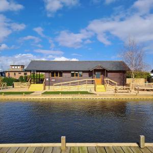 a house with a dock next to a body of water at River Breeze - Norfolk Broads in Brundall