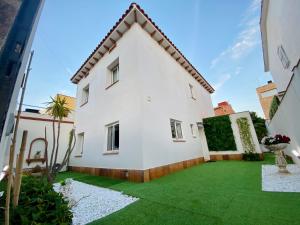 ein großes weißes Haus mit einem grünen Hof in der Unterkunft Villa Paradise, urban oasis by -Toprentalsbarcelona- in Esplugues de Llobregat