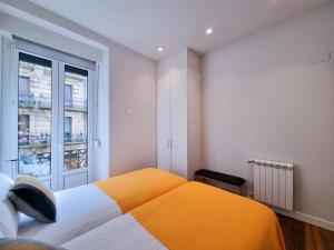 een slaapkamer met een oranje en wit bed en een raam bij Chillida Larramendi - Iberorent Apartments in San Sebastian