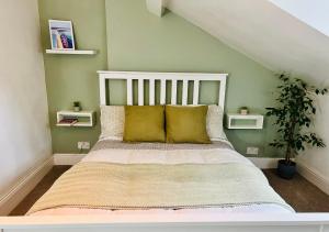 a bed with yellow pillows in a green bedroom at Top Floor Apartment Overlooking Torquay Harbour Pet Friendly in Torquay
