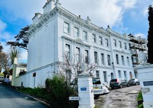 a white building with cars parked in front of it at Top Floor Apartment Overlooking Torquay Harbour Pet Friendly in Torquay