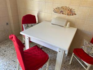 un tavolo bianco con due sedie rosse e un computer portatile di Casa Napoletana a Napoli