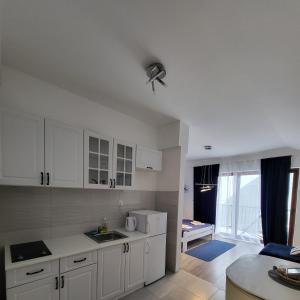 a kitchen with white cabinets and a living room at Apartmani Sport Igalo in Herceg-Novi