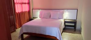 1 dormitorio con 1 cama grande con sábanas y almohadas rosas en RH02 Riohacha apartamento con vista al mar en la mejor zona de la ciudad genial para relax o trabajo, en Ríohacha