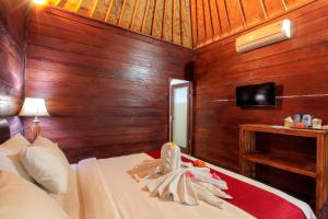 a bedroom with wooden walls and a bed and a television at THE DARA HILL in Nusa Penida