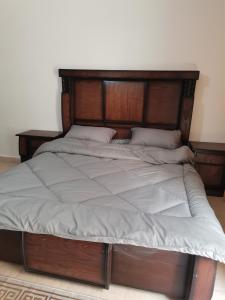 a large bed with a wooden headboard in a bedroom at Studeo for rent in Amman