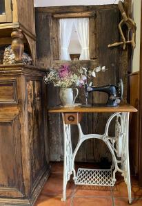 una mesa con una máquina de coser y flores en ella en HOTEL RURAL EL SABINAR en Crémenes