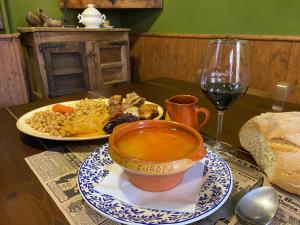 una mesa con un plato de comida y una copa de vino en HOTEL RURAL EL SABINAR en Crémenes