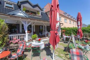 a patio with tables and umbrellas in front of a house at cafesahne u Pension in Dranske