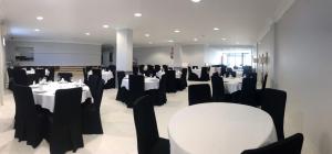 uma sala de jantar com mesas brancas e cadeiras pretas em Hotel Bradomin em Vilanova de Arousa