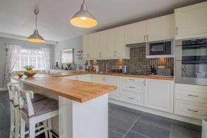 a kitchen with white cabinets and a wooden counter top at Pear Tree House in Beeston