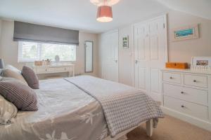 a bedroom with a bed with a dresser and a window at Pear Tree House in Beeston
