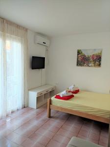 Guest House Lotos في بيشيشي: غرفة بيضاء فيها سرير وتلفزيون