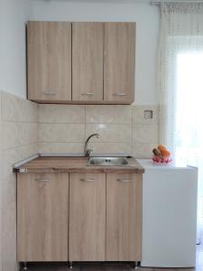 een keuken met houten kasten en een wastafel bij Guest House Lotos in Becici