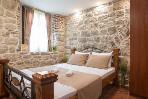 - une chambre avec un lit et un mur en pierre dans l'établissement Little Bay Apartments, à Kotor