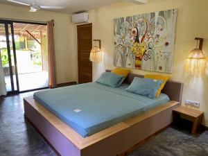 a bed in a room with a painting on the wall at La perle rare de Nosy be in Ambatoloaka