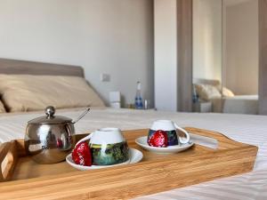 a tray with two tea pots and strawberries on a bed at APPARTAMENTO DE LUXE GIADA in Bologna