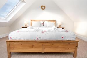 una camera da letto con un grande letto con lenzuola bianche di The Barn a Bala