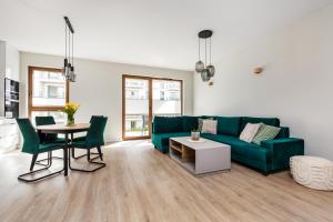 a living room with a green couch and a table at Uroczy ,,Bursztynowy ,, apartament blisko plaży , parking w cenie in Gdańsk