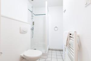 a white bathroom with a toilet and a shower at Cerise Nantes Atlantis in Saint-Herblain