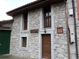 un edificio de piedra con una puerta y ventanas marrones en La Xiana, en Taranes