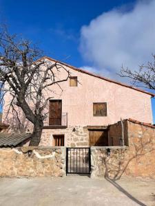 duży ceglany budynek z drzewem przed nim w obiekcie Acogedora casa con patio-parking w Albarracín