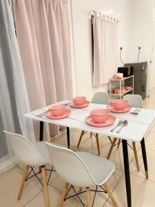a white table with pink bowls and white chairs at Homestay Balik Pulau 2.0 3BedRoom in Balik Pulau