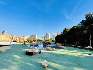 a swimming pool in a park with a city in the background at A935 - La Cala in Villajoyosa