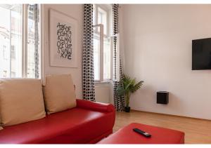a living room with a red couch and a tv at Viennese 3BR shared Apt. Near Wiener Stadthalle & Central in Vienna